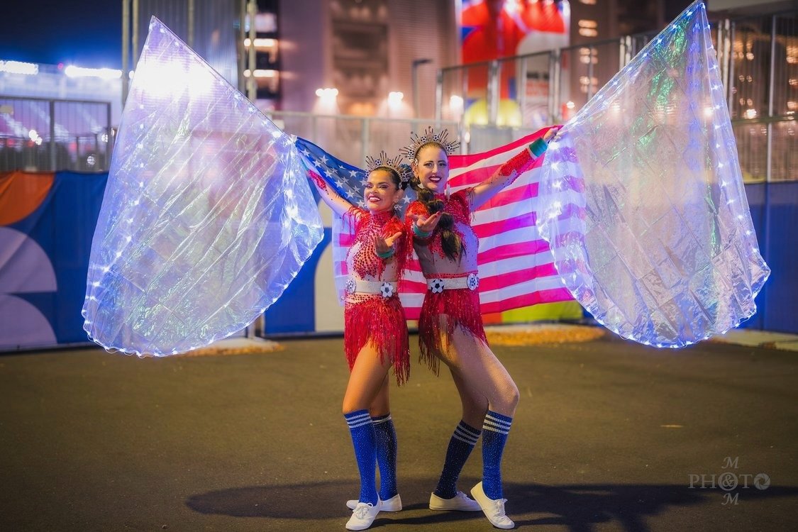 Two specialty performers with American flag and illuminated LED wings during a 2026 World Cup event